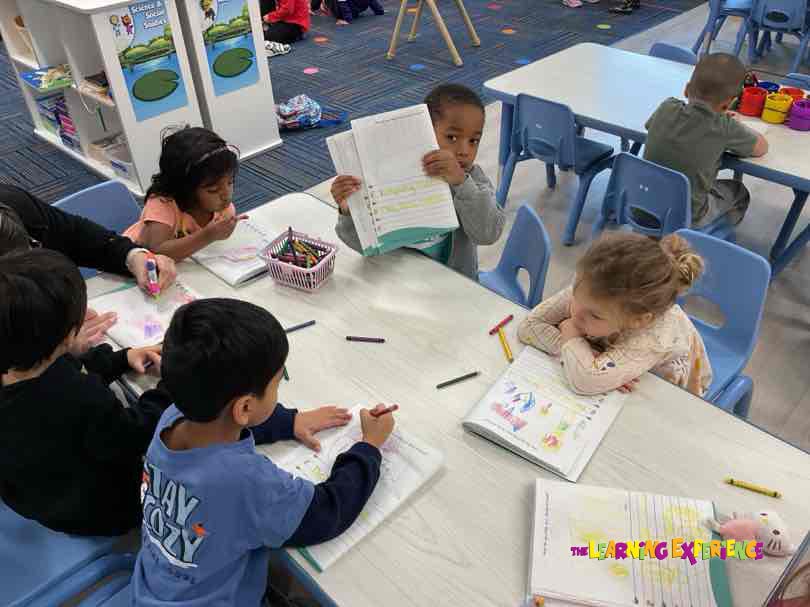Children working on papers at tables in a classroom