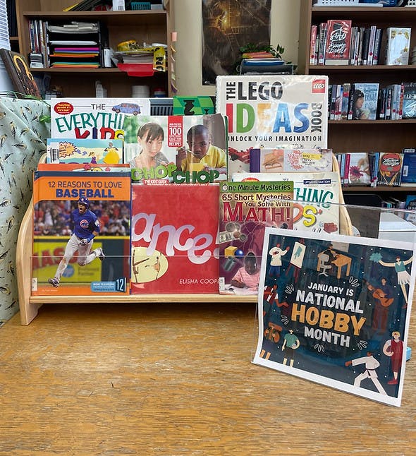 Books in a display rack with a sign that reads January is National Hobby Month