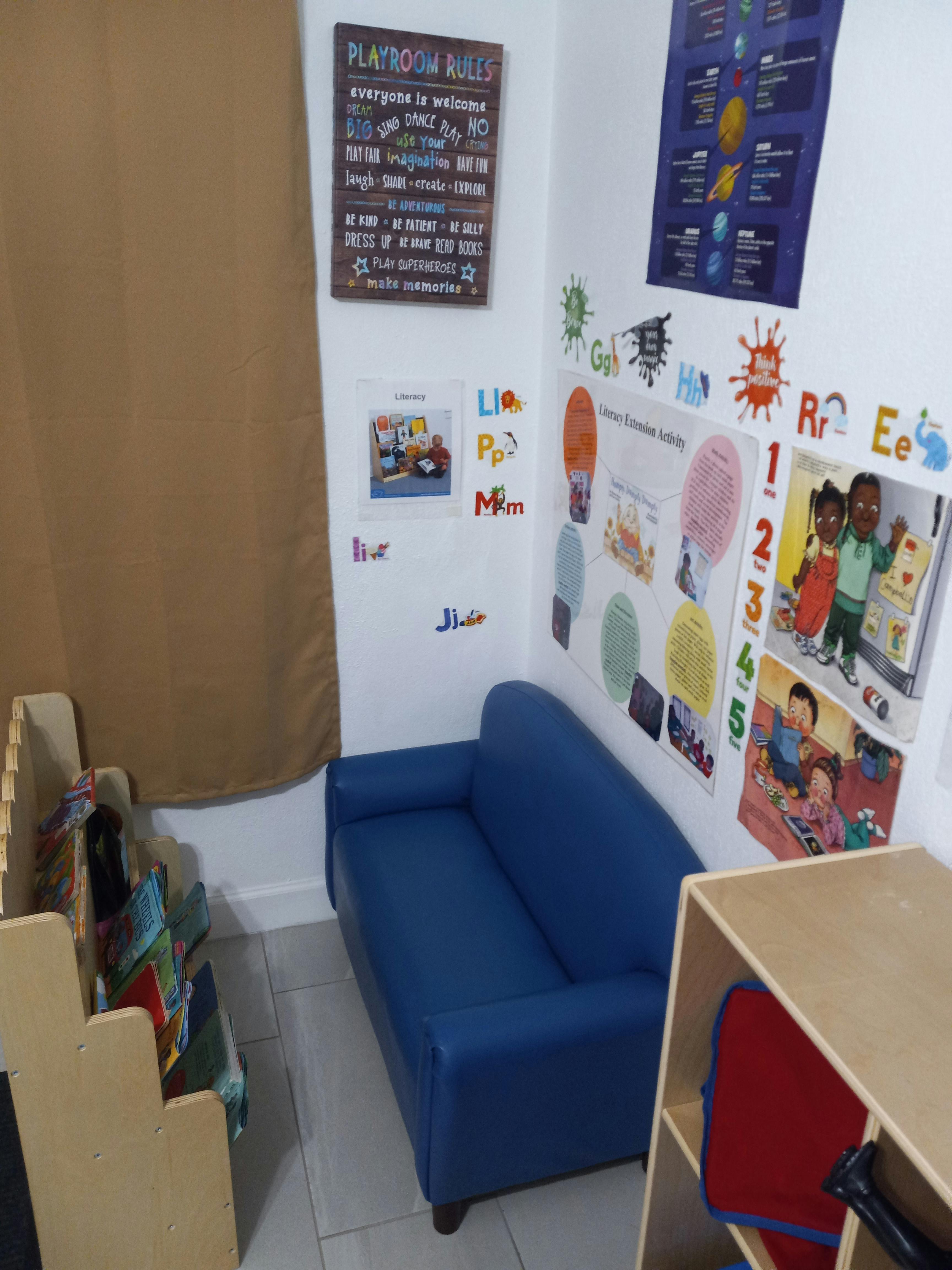 Playroom with a blue couch, educational posters, and a "Playroom Rules" sign