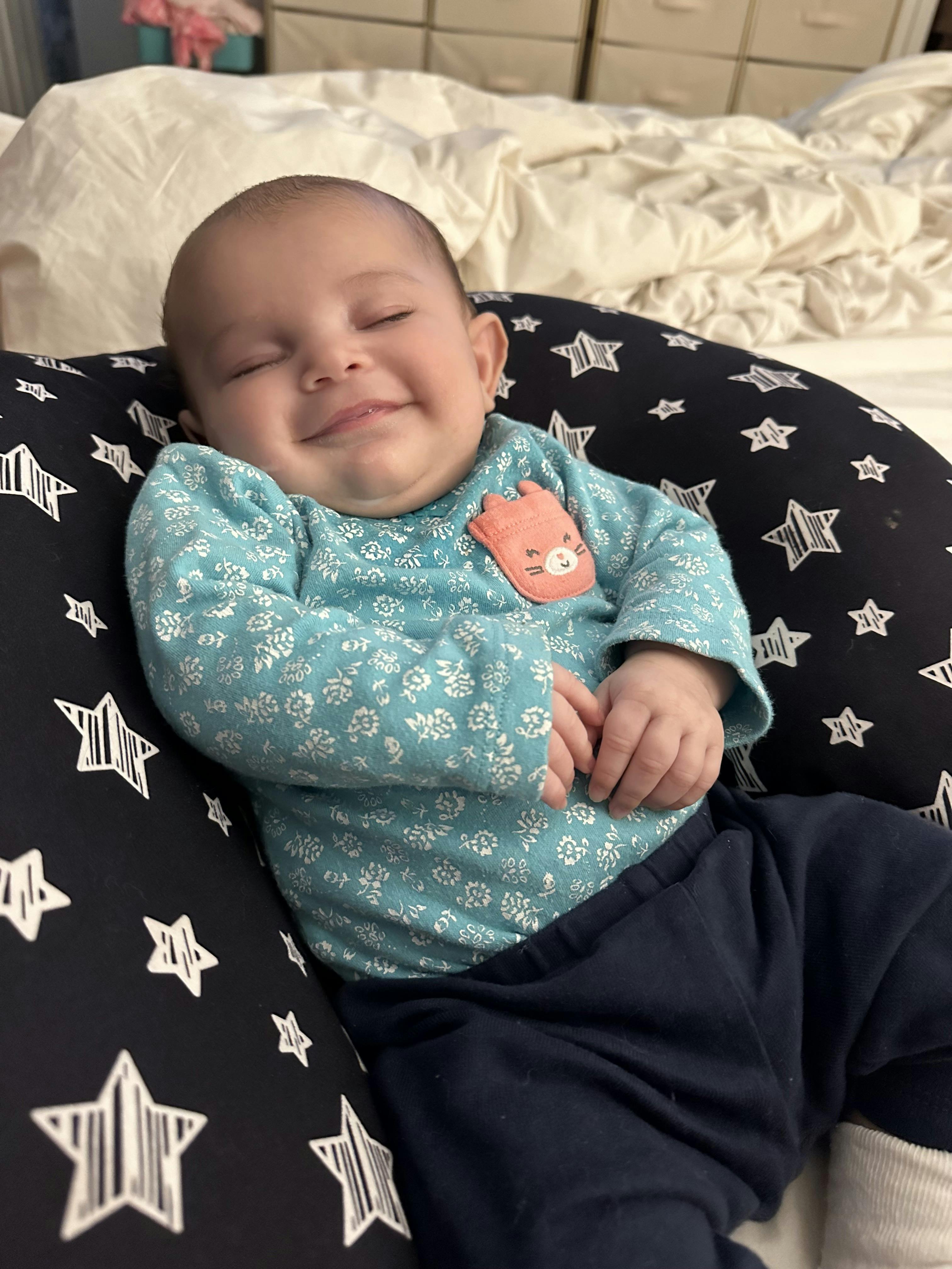 Child with eyes closed, smiling while sitting in a star-patterned pillow