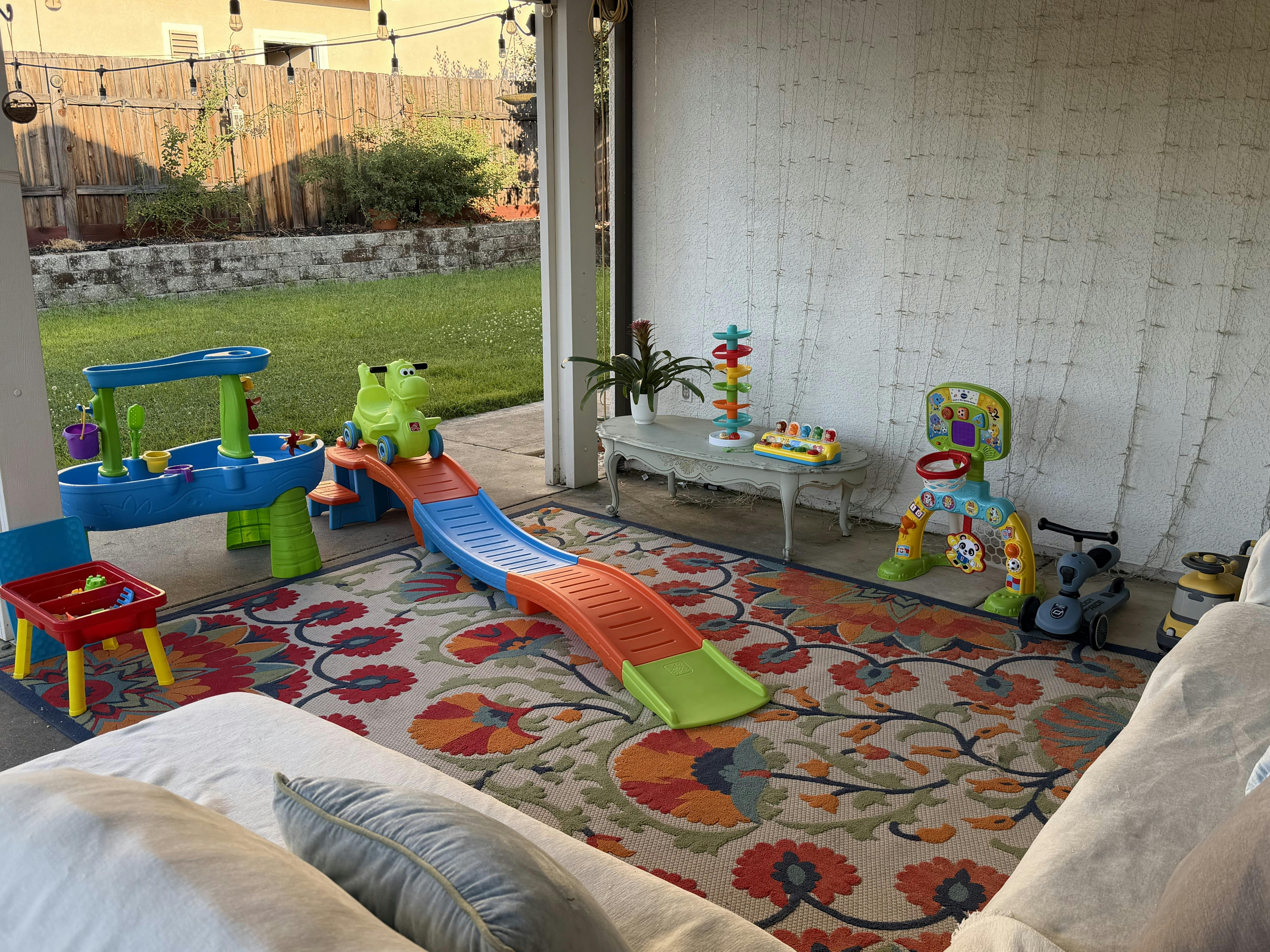 Children's toys arranged on a patterned rug in a covered outdoor patio