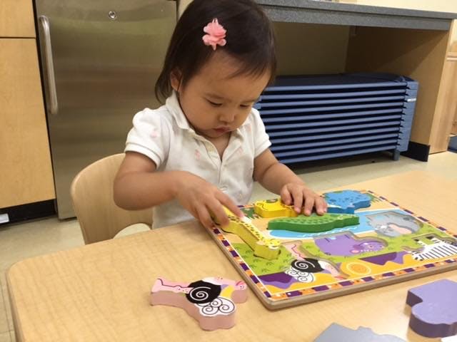 Child playing with a wooden puzzle at a table