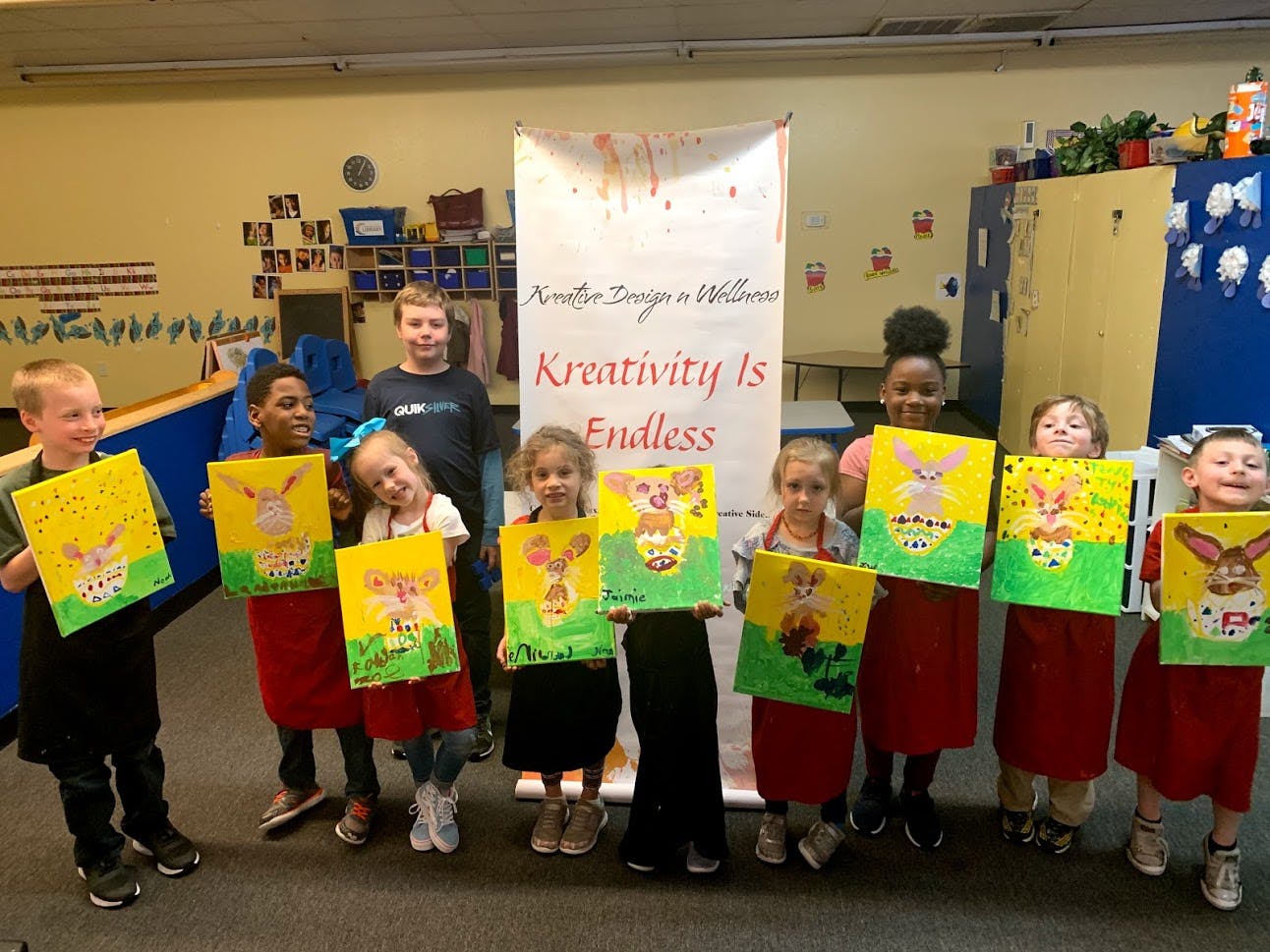 Group of children holding up their paintings of bunnies in eggs