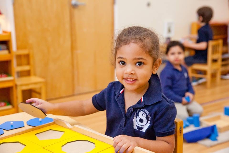 Child playing with a shape sorter in a classroom