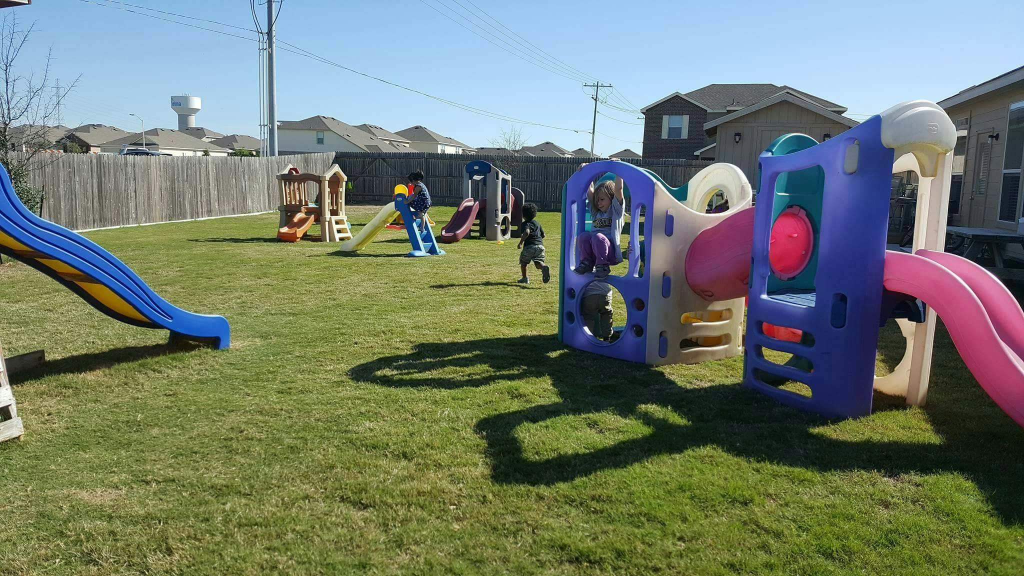 Children playing on playground equipment in a grassy yard