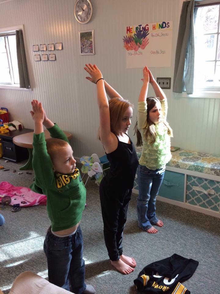 Three children standing with arms raised