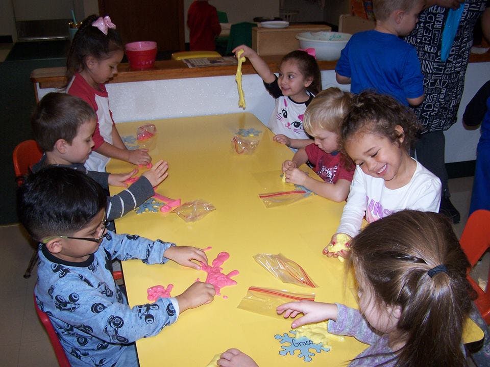 Children at a yellow table making crafts
