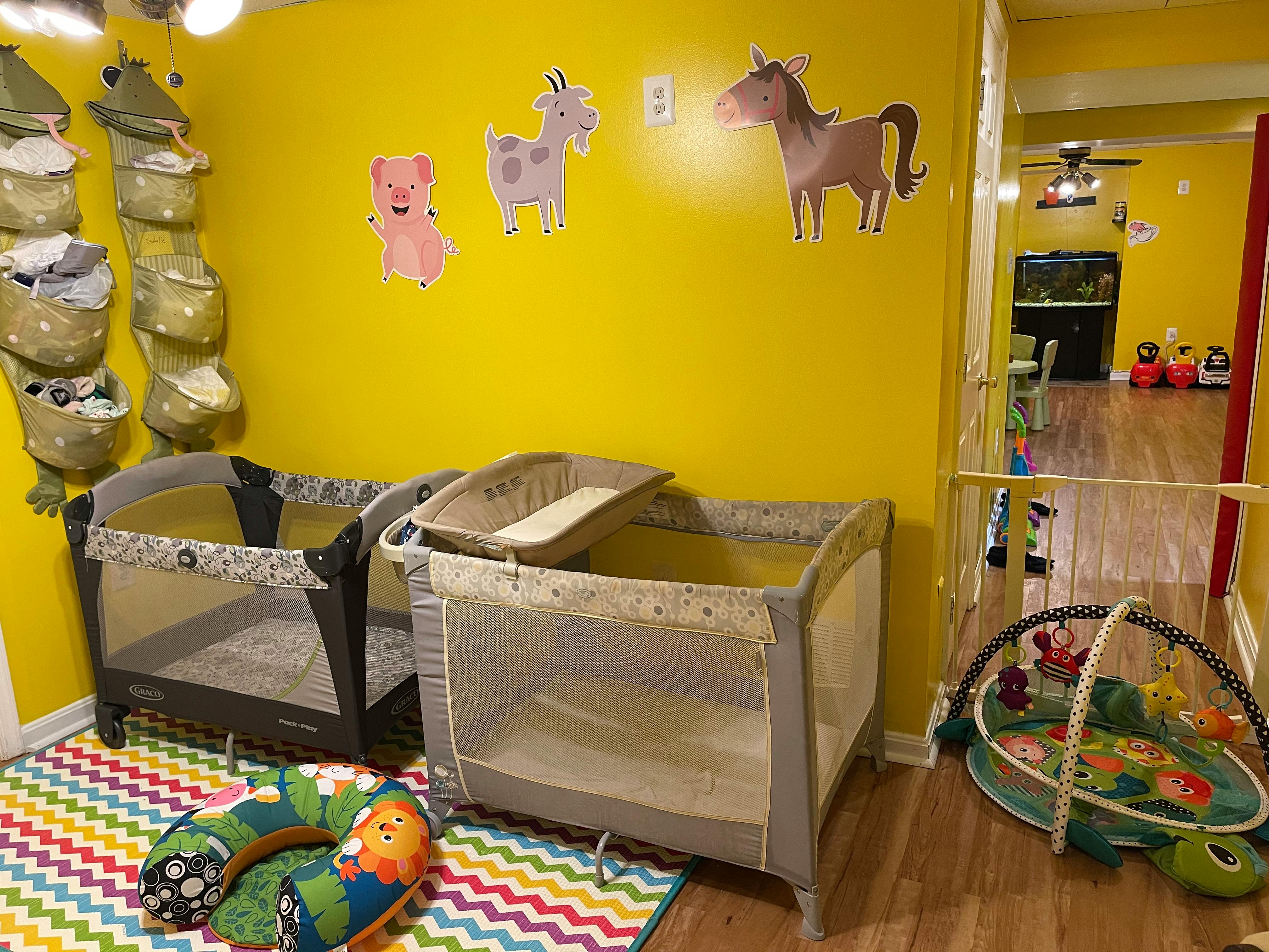 Two playards and a baby activity mat in a room with yellow walls