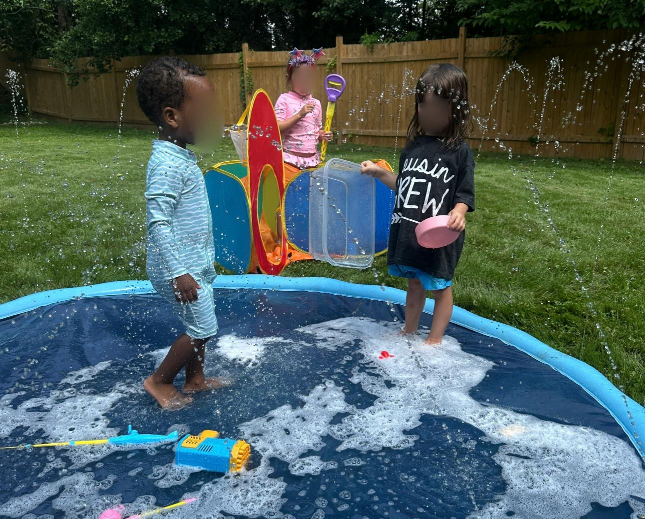 Children playing in a shallow pool with water spraying