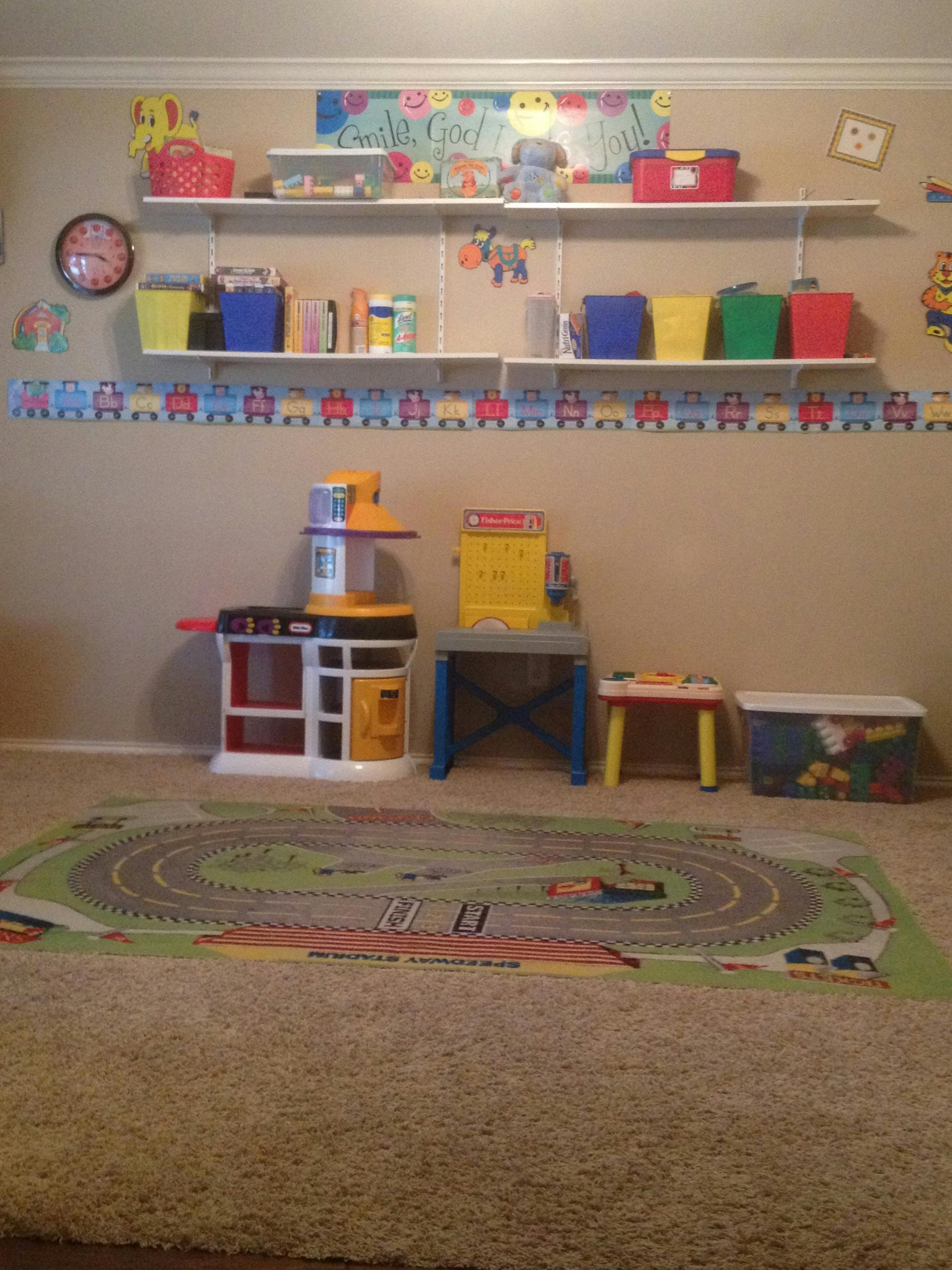 Playroom with shelves of toys, play kitchen, and train rug
