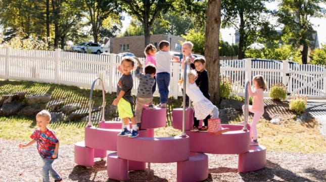 Children playing on a pink climbing structure outdoors