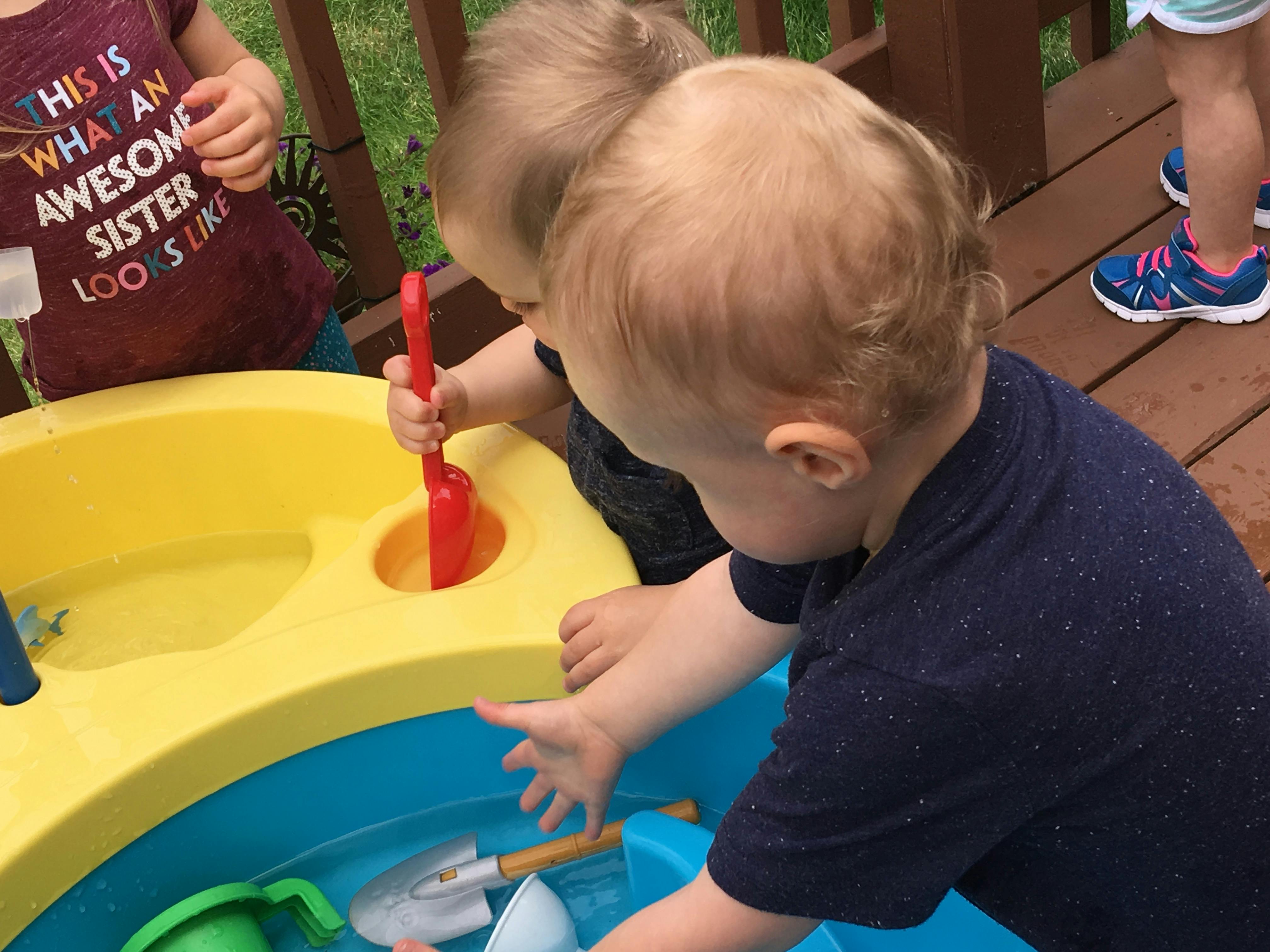 Two children playing with a water table