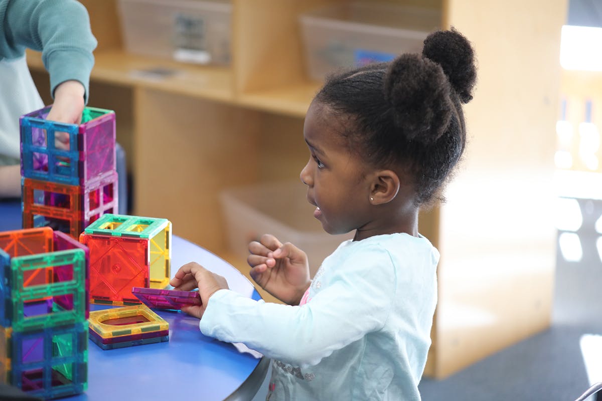 Child playing with colorful magnetic blocks at a table