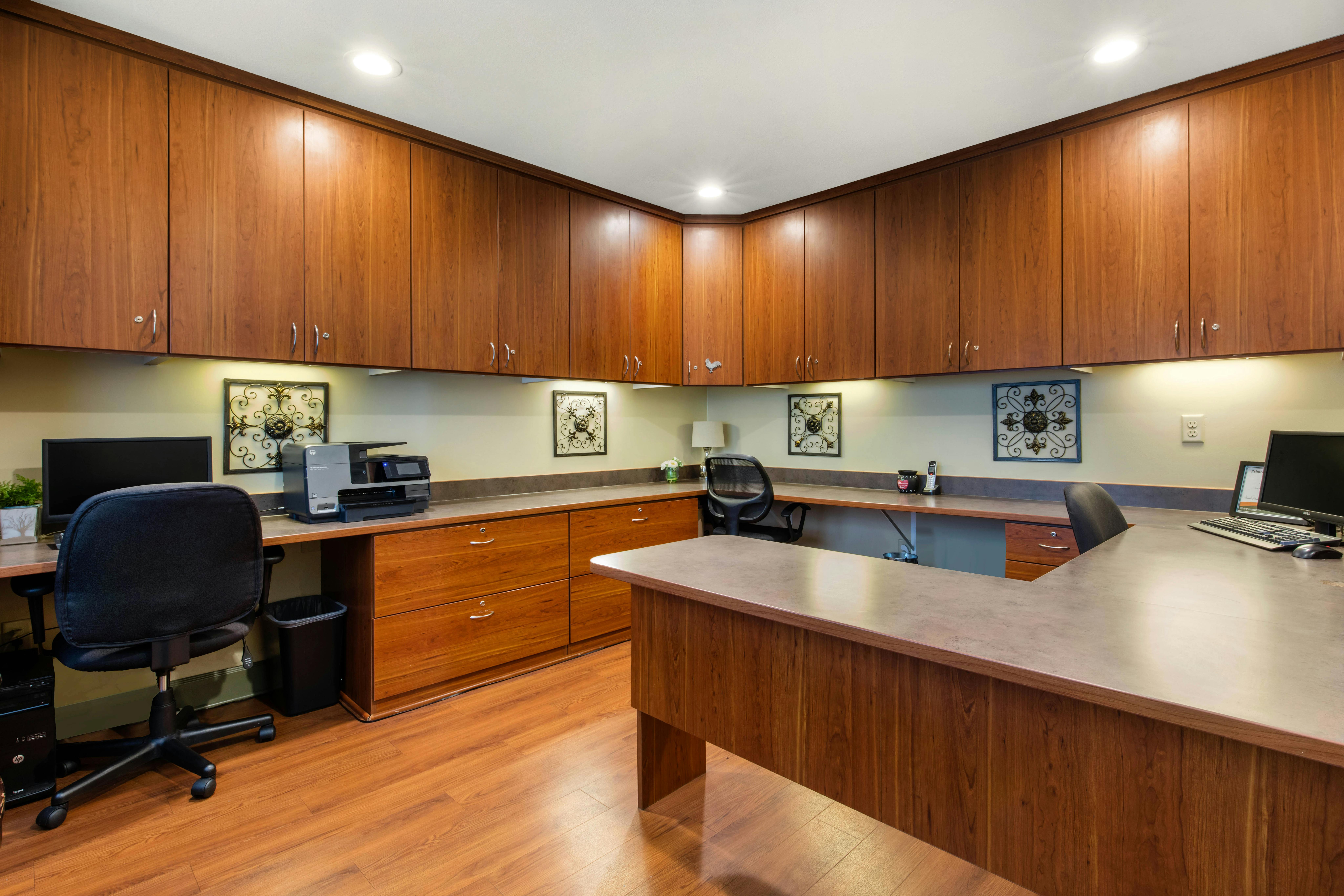 Home office with wood cabinets, desk with multiple computer monitors