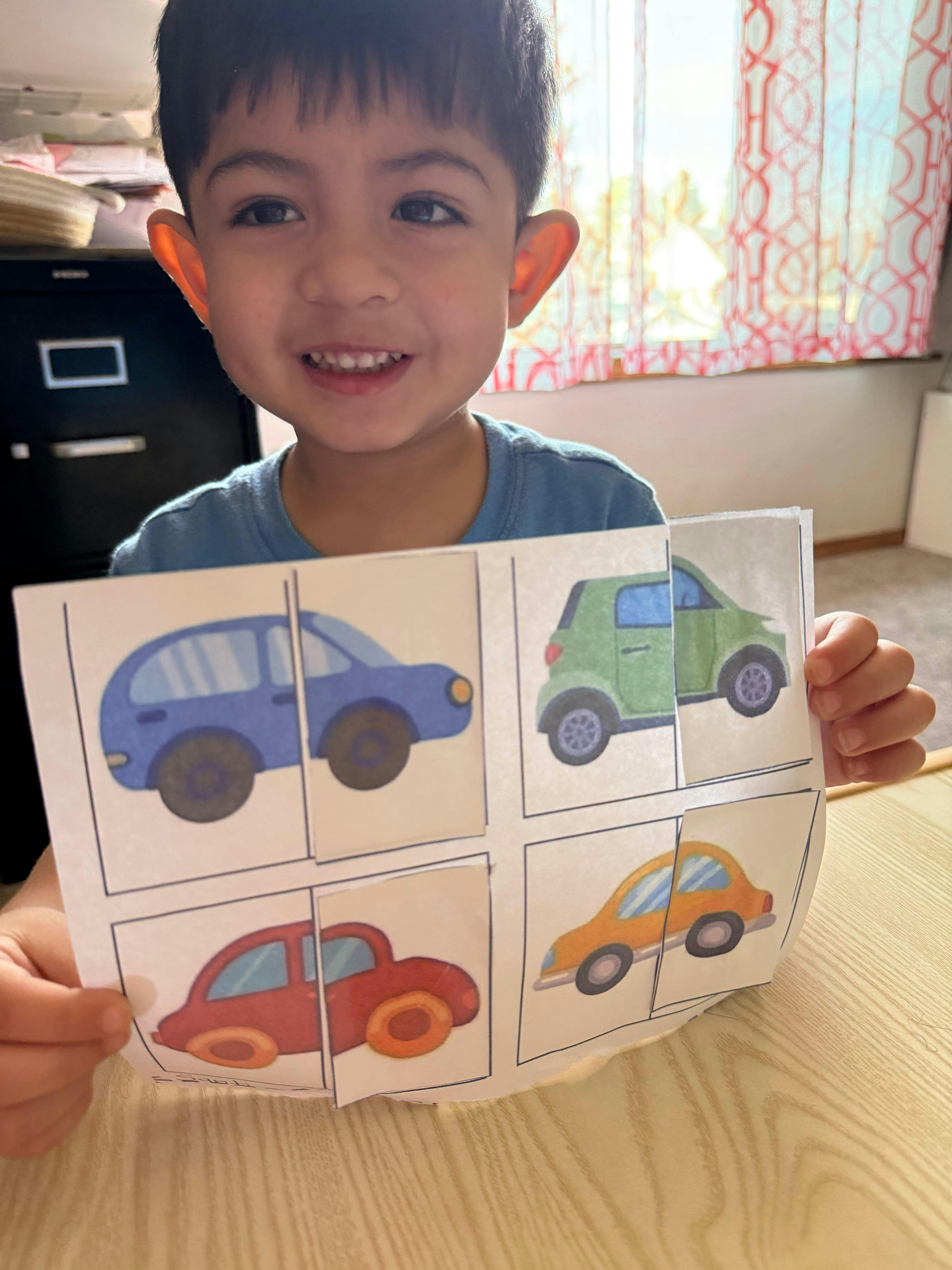 Child holding a page with matching car puzzle pieces