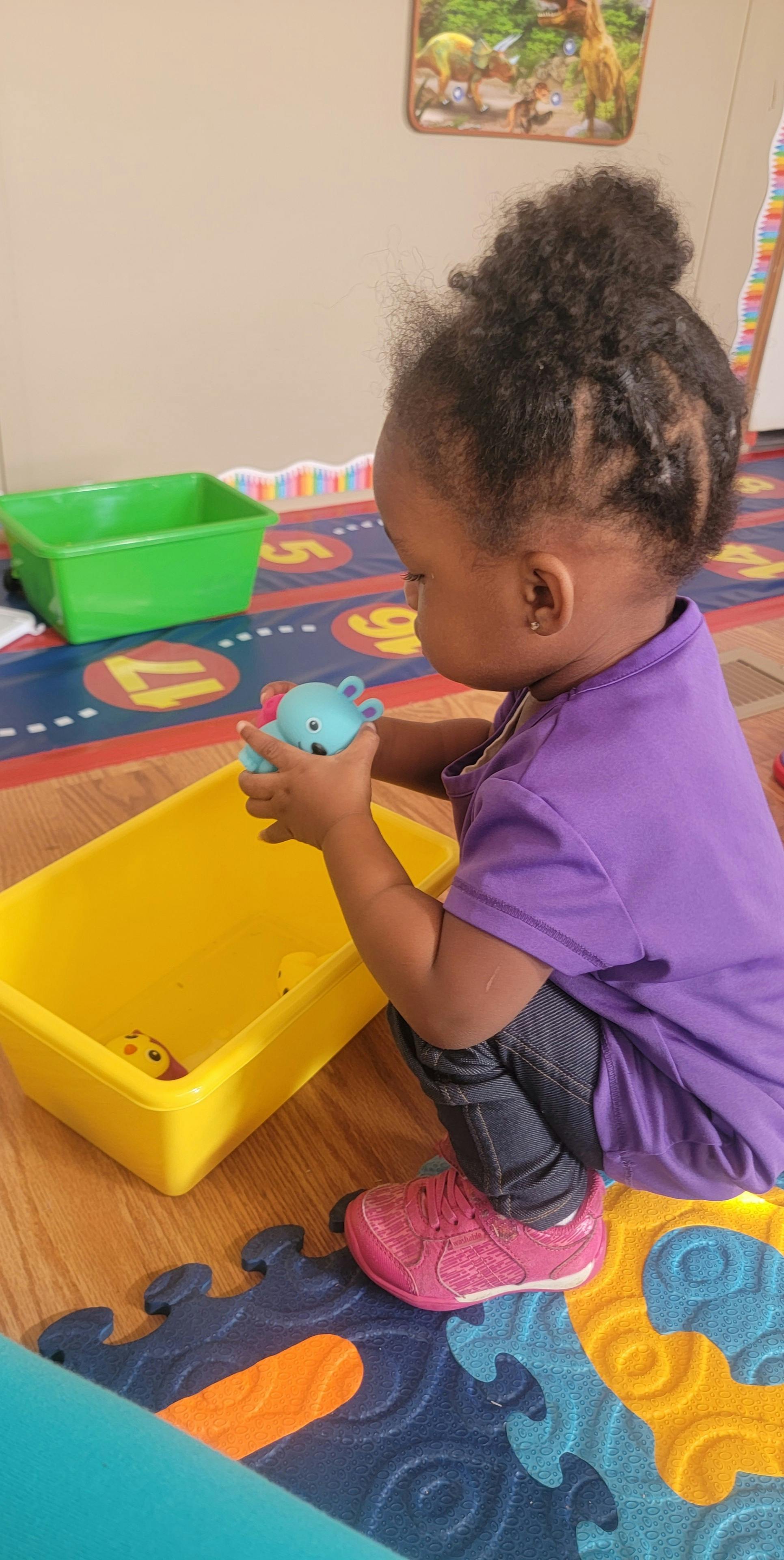 Child playing with a toy over a yellow bin