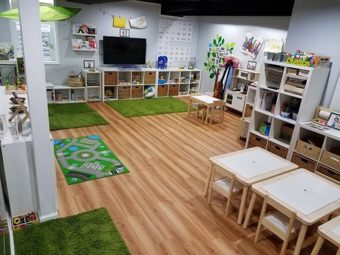 Playroom with green rugs, small tables, and storage shelves