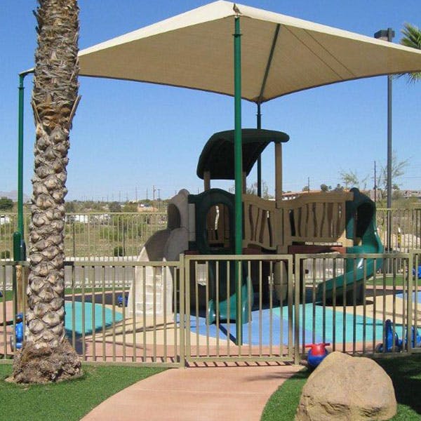 Playground with slides and climbing structures under a large shade canopy