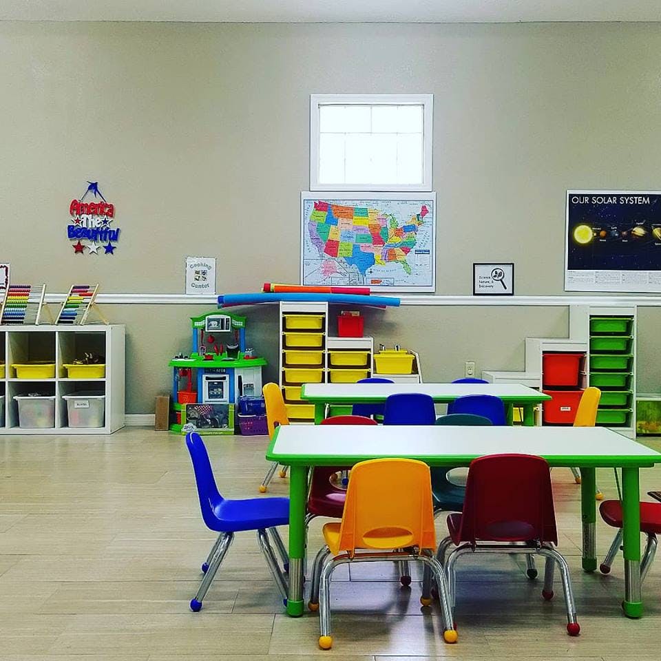 Classroom with small tables and chairs, storage units, and wall maps