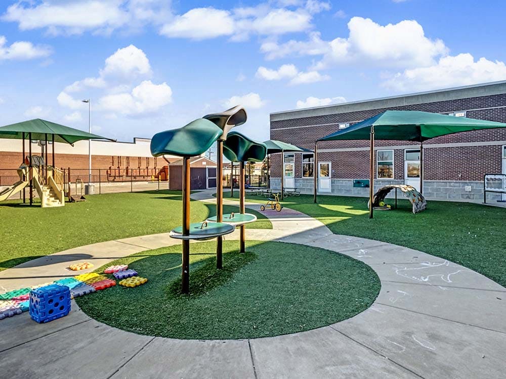 Outdoor playground with artificial turf, slides, and shaded areas