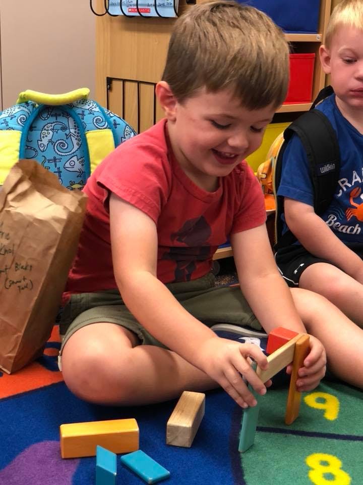 Child playing with colorful wooden blocks on a rug