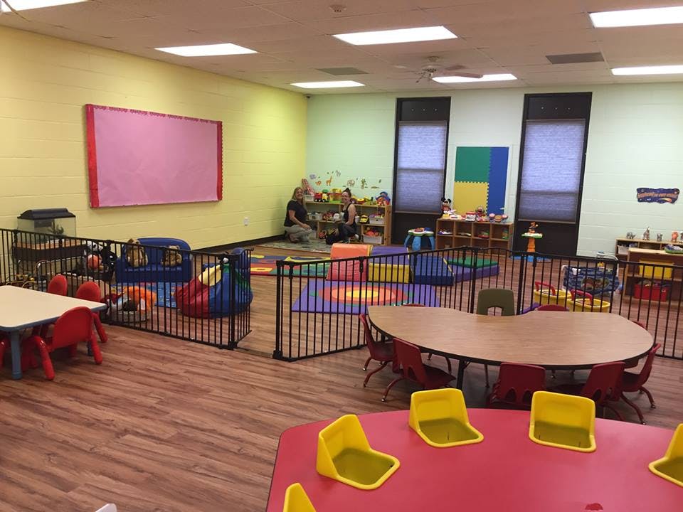 Playroom with tables, chairs, and fenced play areas