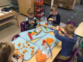 Four children playing with modeling clay at a table