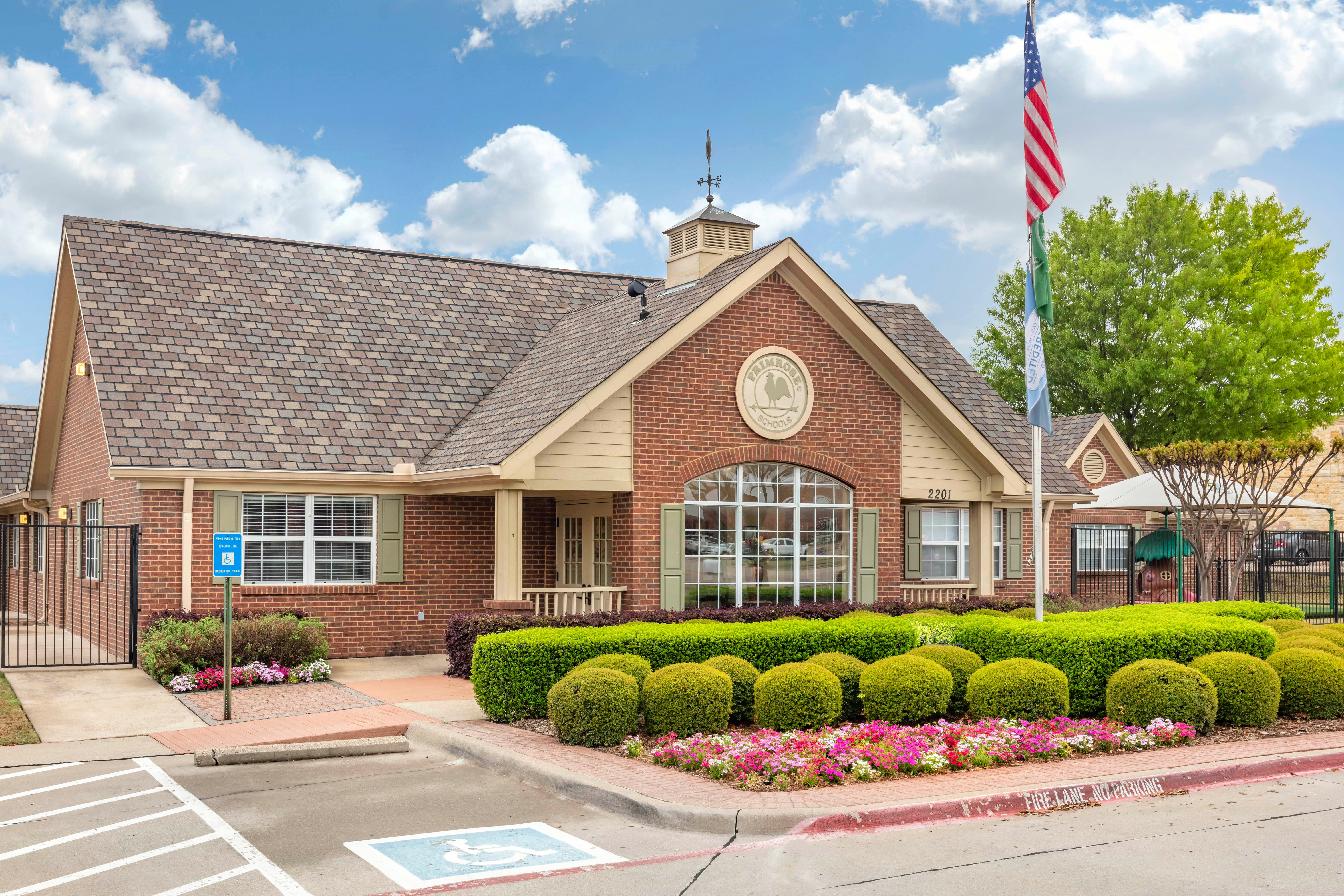 Exterior of a brick building with a brown roof and a circular Primrose Schools sign
