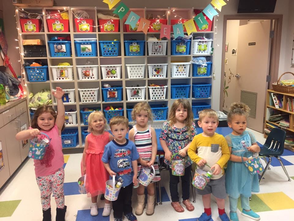 Six children holding baskets in a classroom