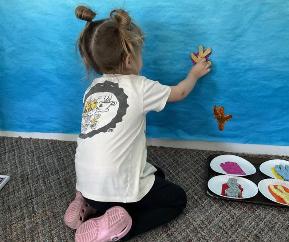 Child kneeling and placing a shape on a blue background
