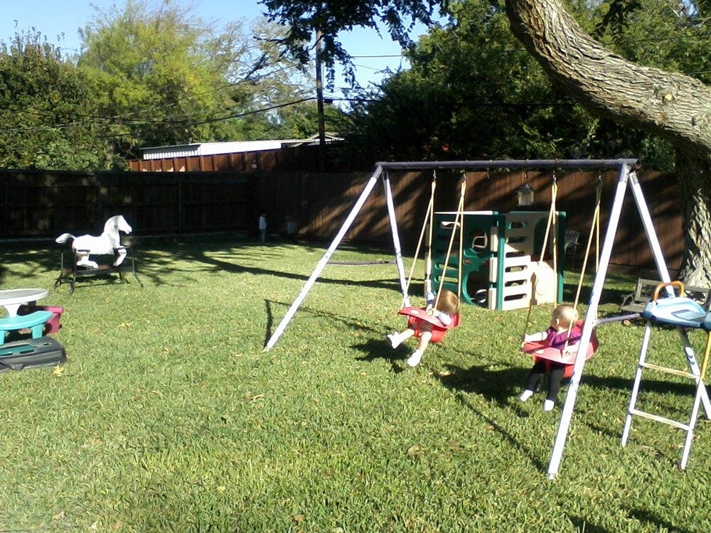 Two children on swings in a backyard