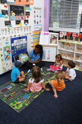 Adult and children sitting on floor in classroom