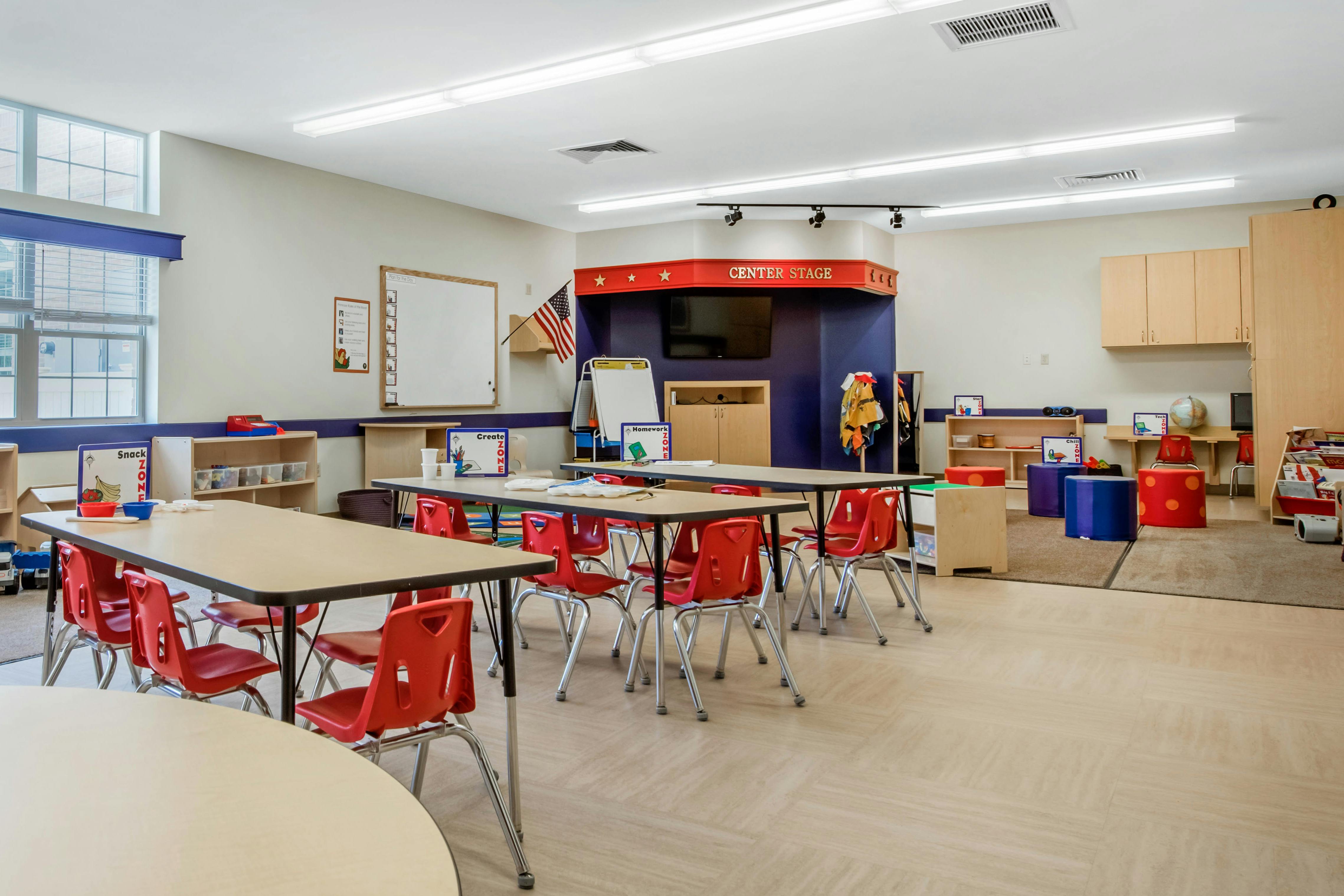Empty classroom with red chairs, tables, and a "CENTER STAGE" area