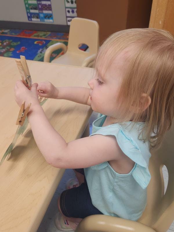 Child sitting at a table playing with clothespins
