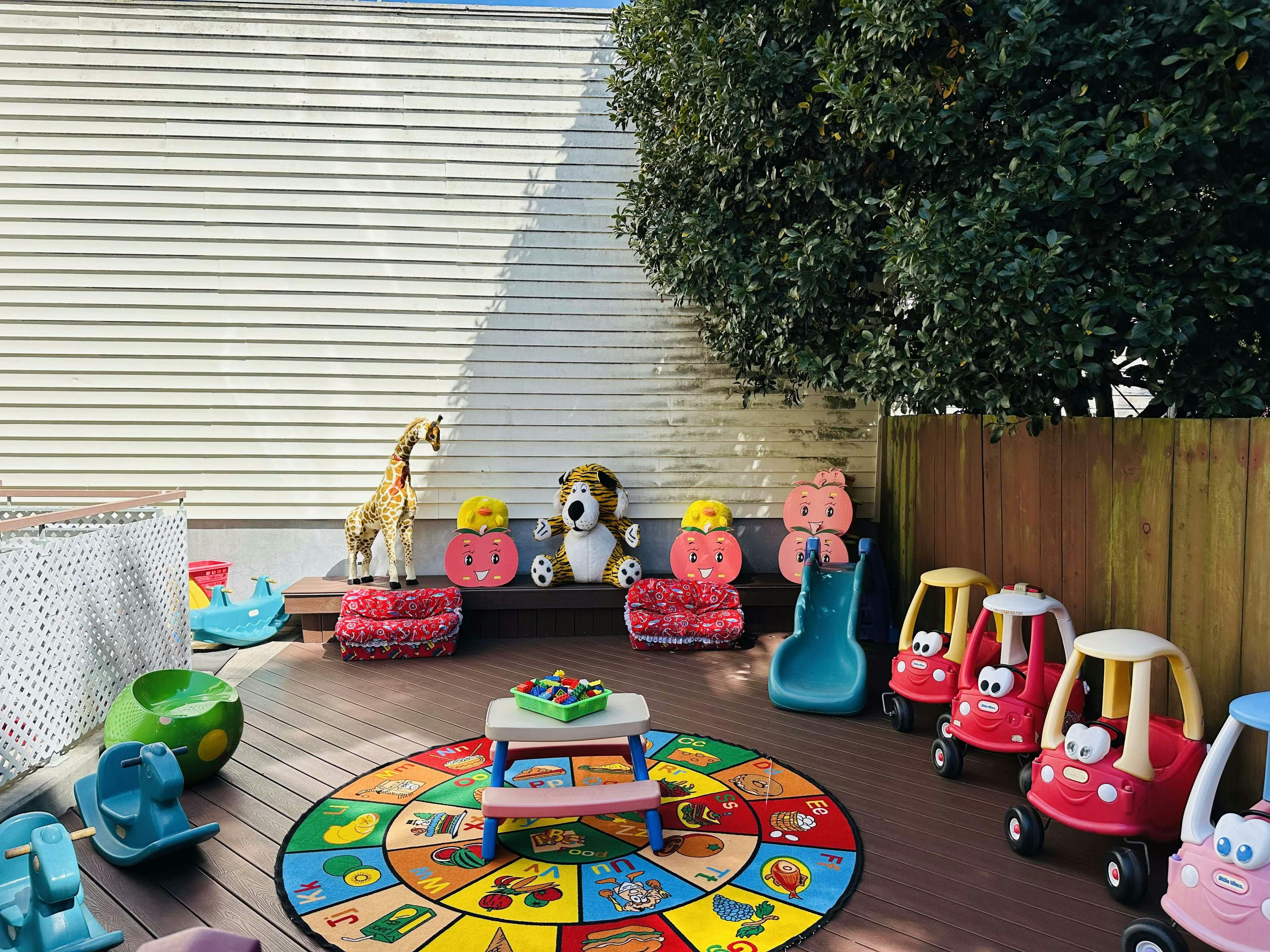 Outdoor children play area with toy cars and a colorful alphabet rug