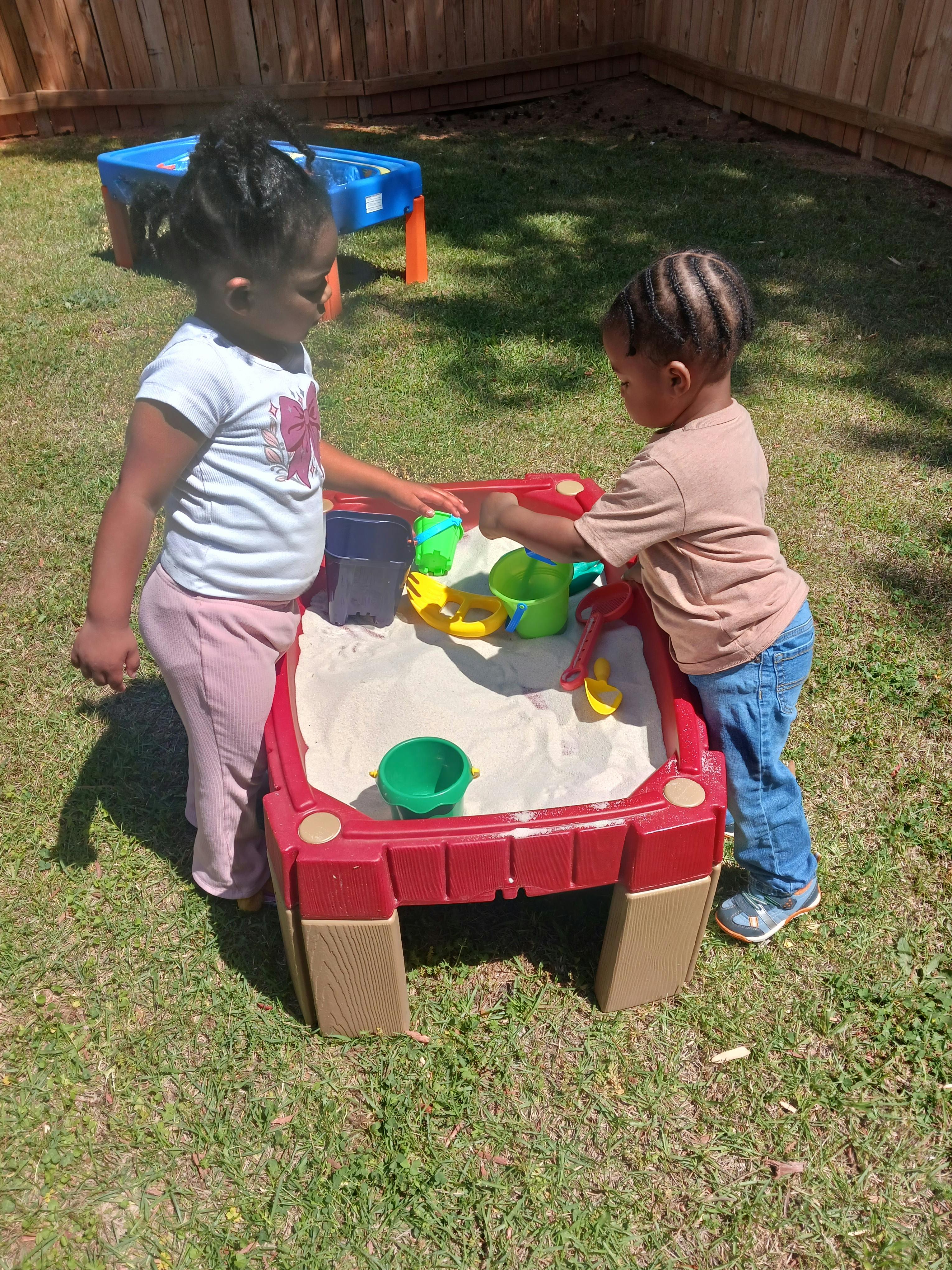 two children playing with sand toys in a sandbox
