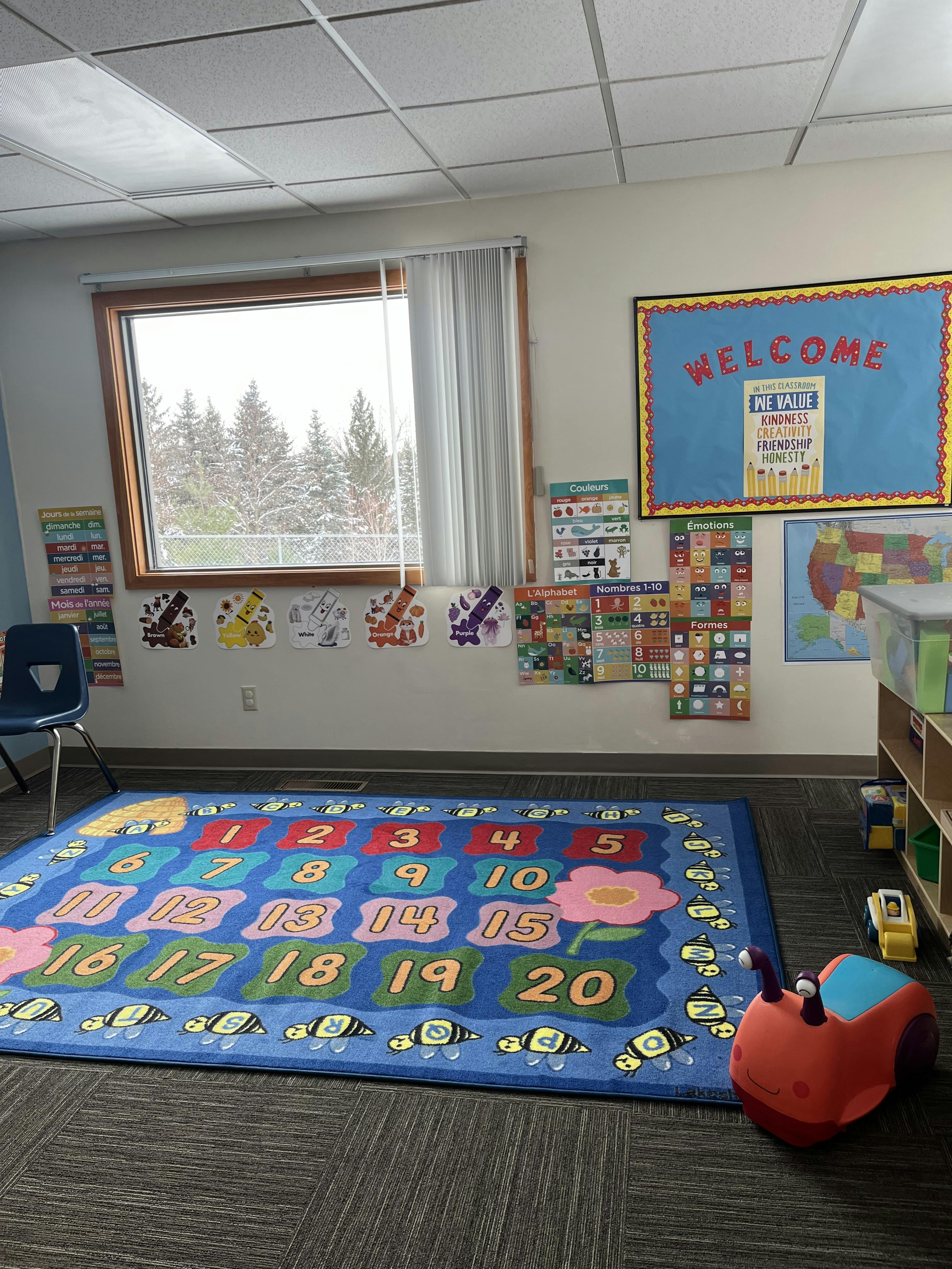 Classroom with a colorful number rug, alphabet and color charts on the wall