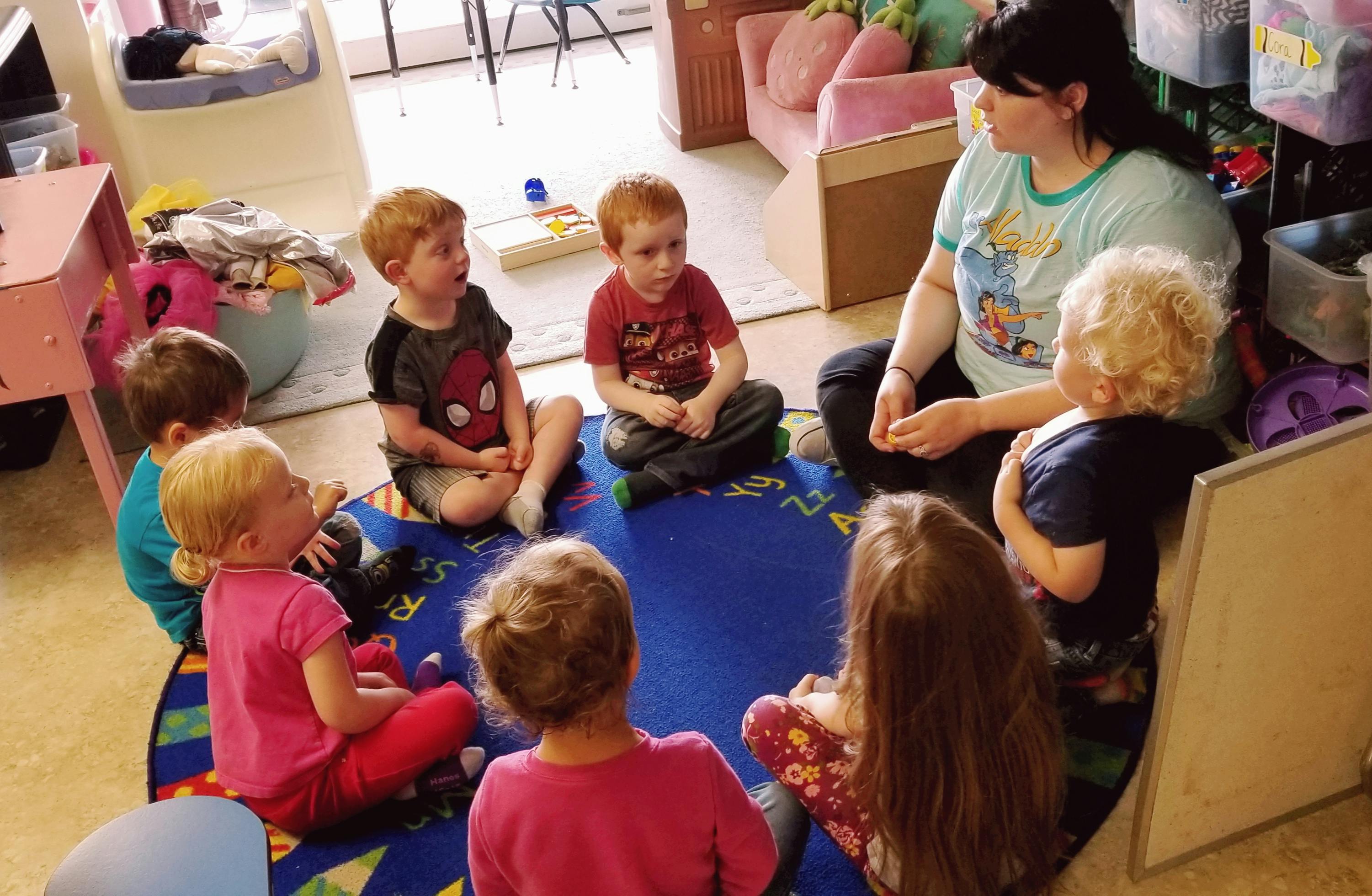 Adult and children sitting in a circle on a rug