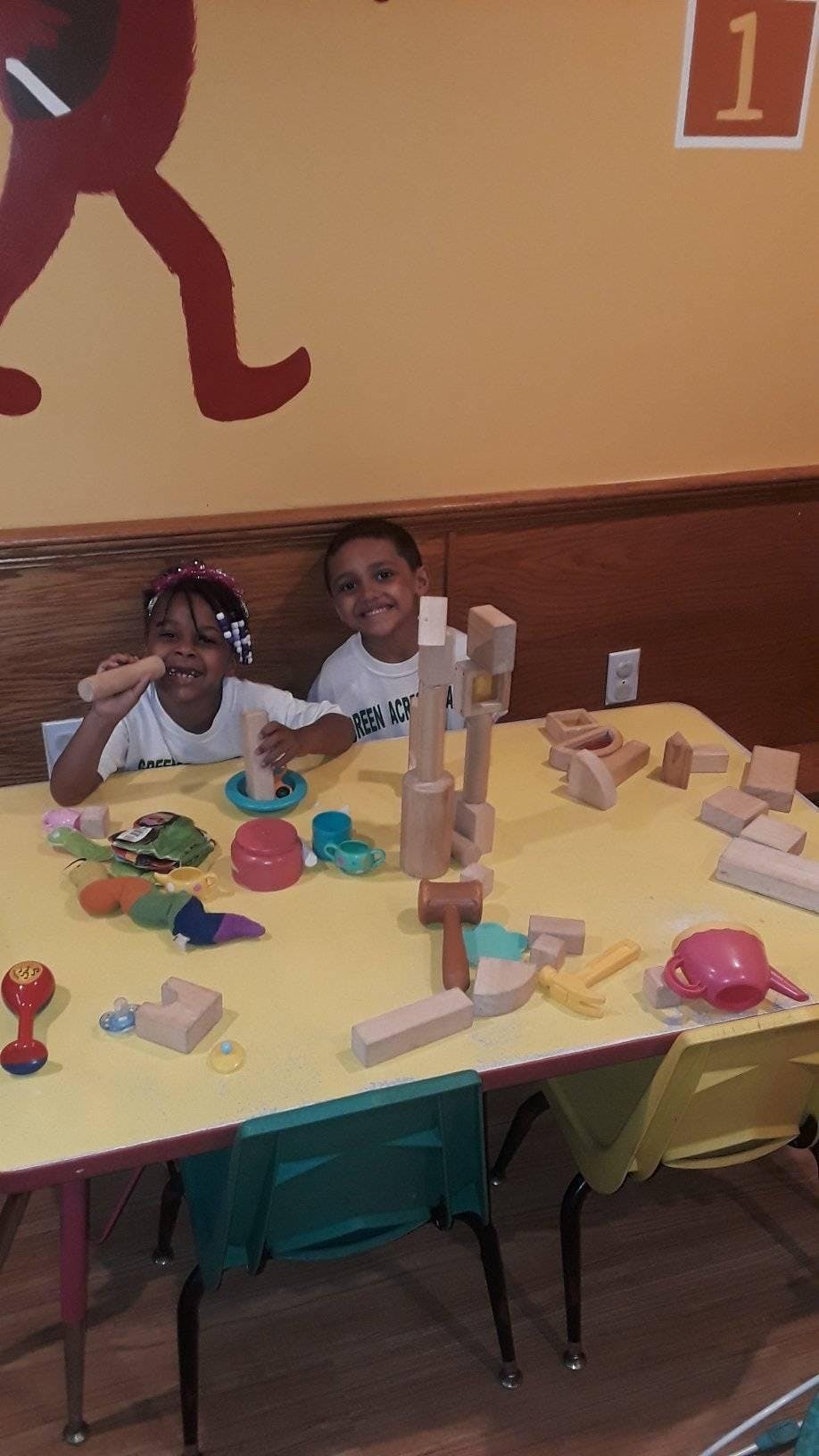 Two children playing with blocks and toys at a table