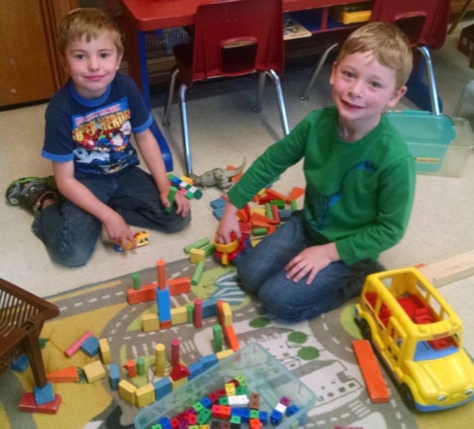 Two children playing with blocks and toys on a rug