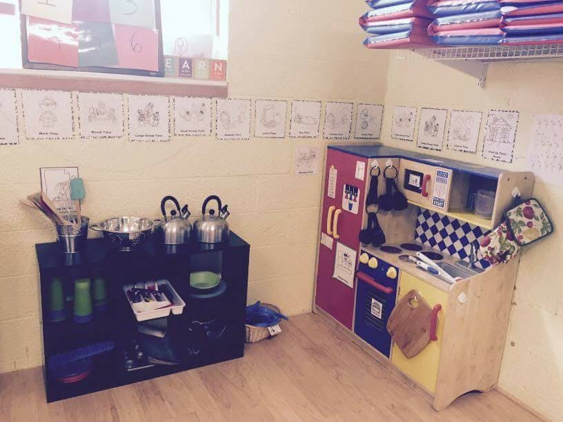 Play kitchen and shelf with toy pots and kettles in a room