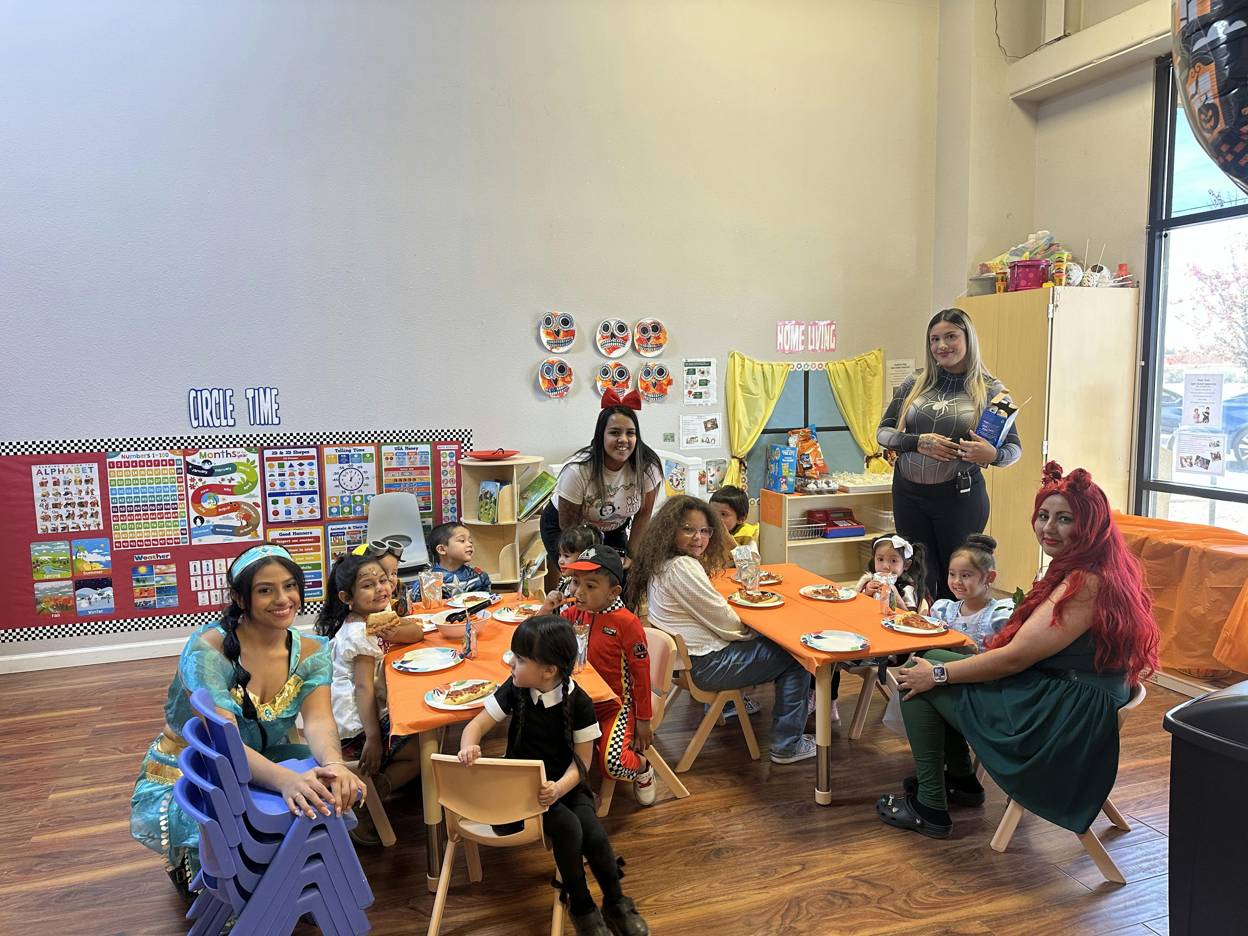 Adults and children sitting at tables in a classroom