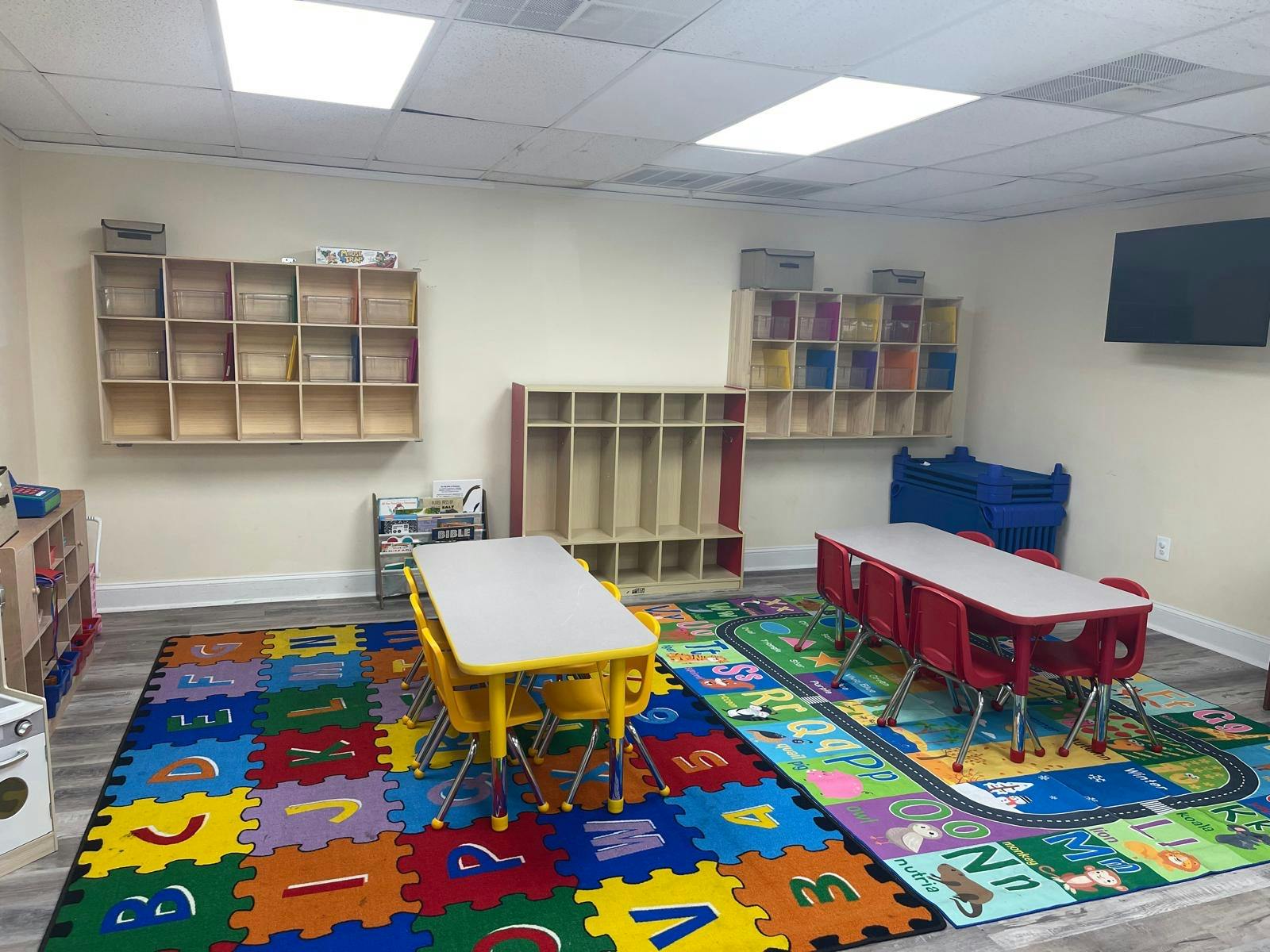 Classroom with colorful alphabet rug, small tables, and storage shelves