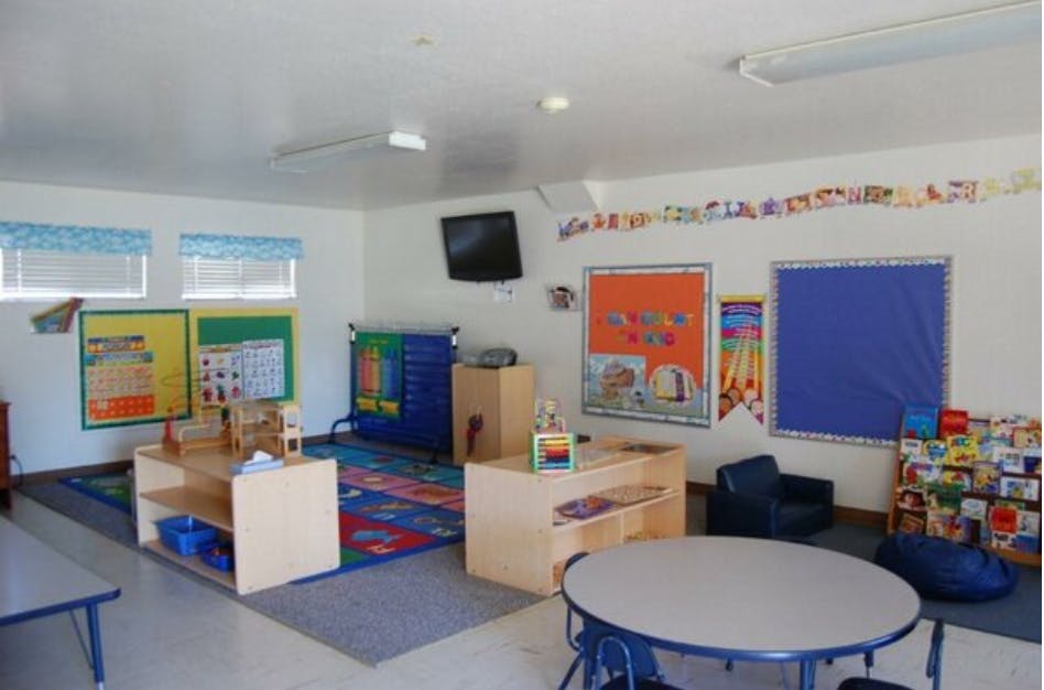 Classroom with small tables, chairs, and educational posters on the walls