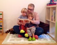 Adult and two children reading a book together