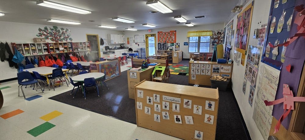 Empty classroom with small tables, chairs, and learning materials