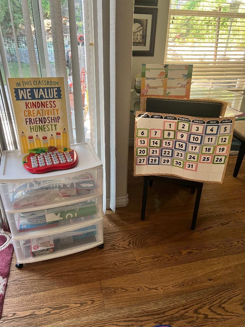 Classroom sign with text "WE VALUE KINDNESS CREATIVITY FRIENDSHIP HONESTY" and a calendar