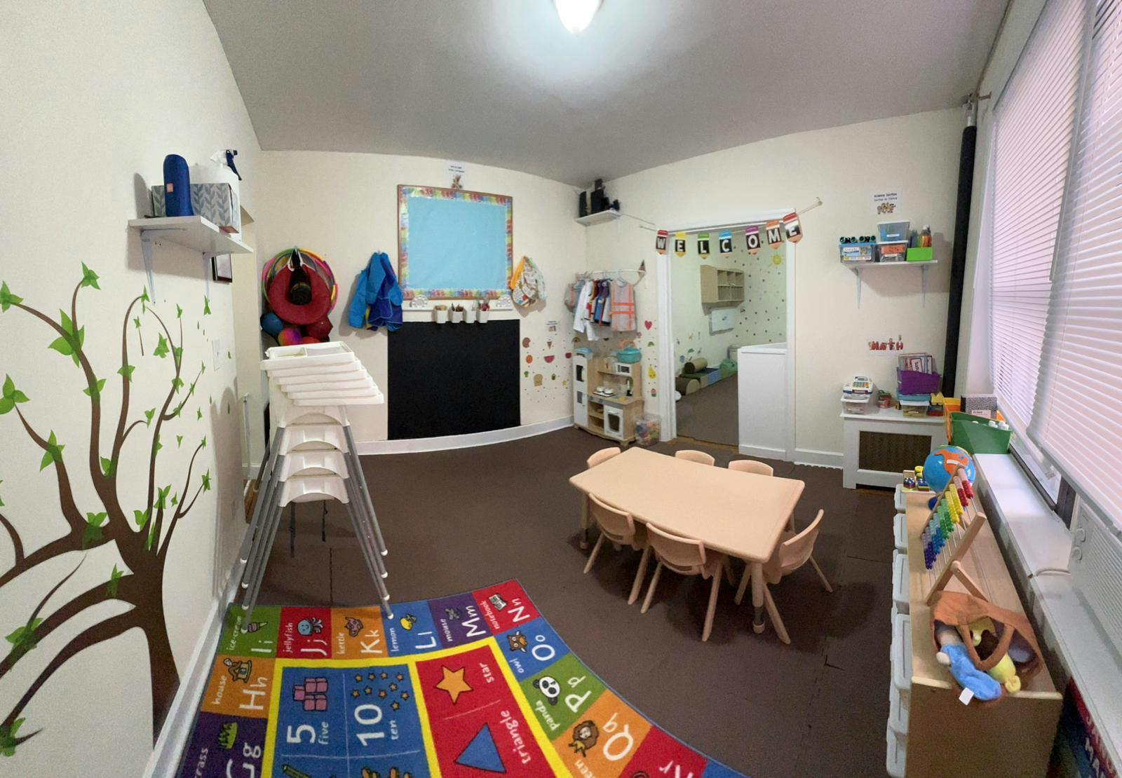 Playroom with a colorful rug, small table and chairs, and a slide