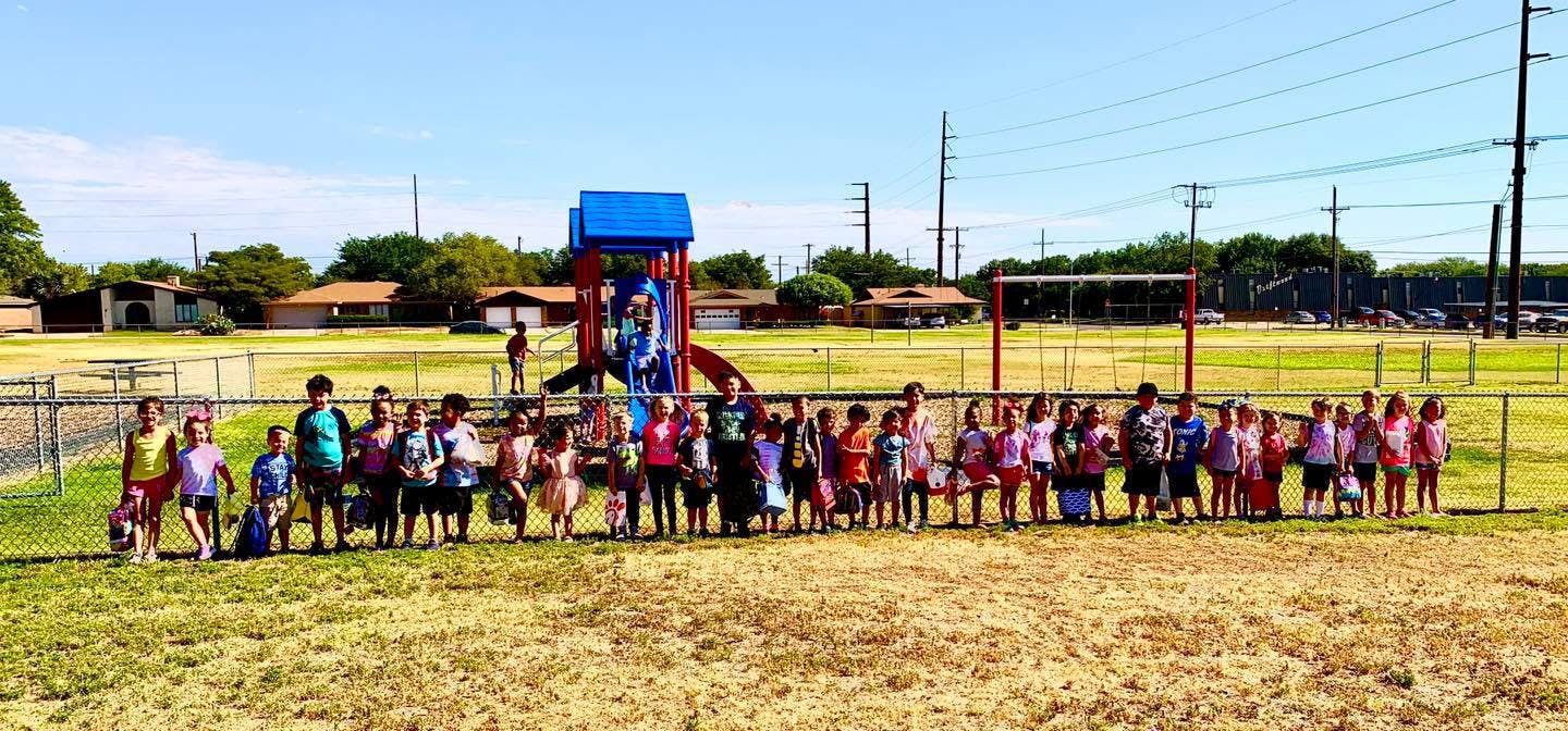 Group of children standing in a field near a playground structure