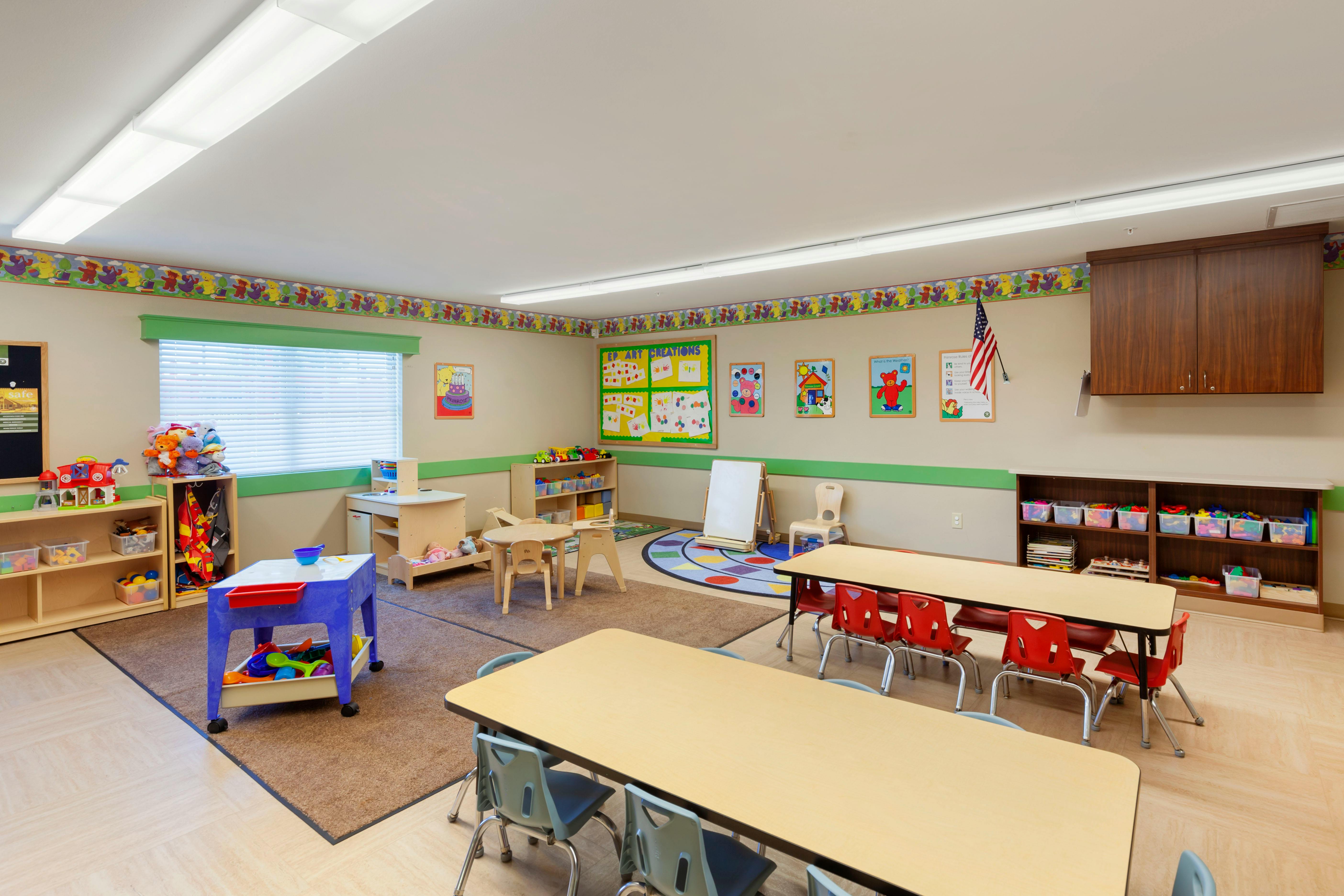 Empty colorful preschool classroom with small tables, chairs, and learning materials